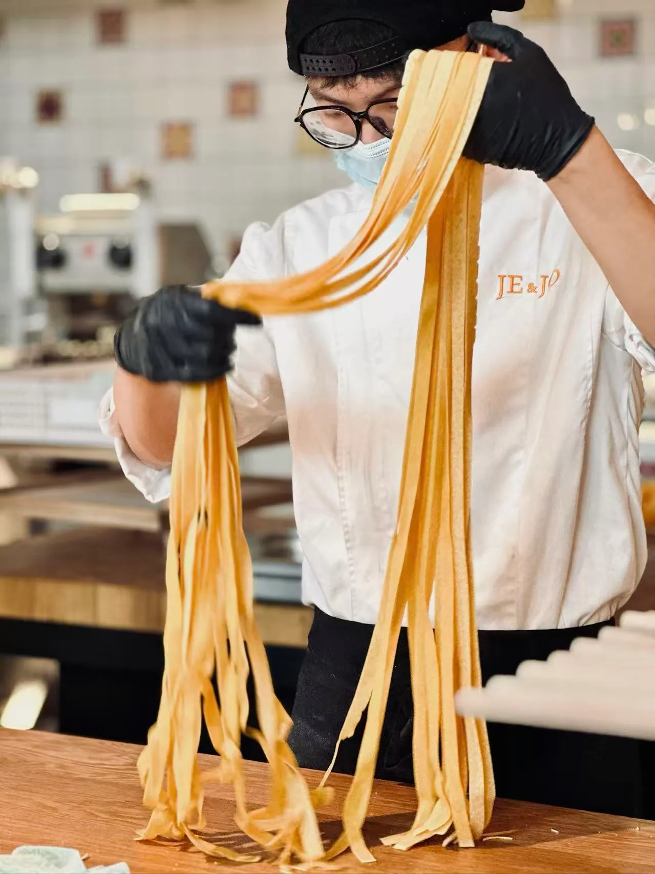 JE&JOの料理人が両手で切りたての生タリアテッレを持ち上げる
