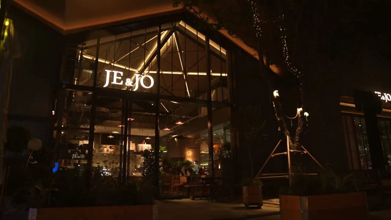 夜のJE&JO店頭、オレンジの看板が灯る